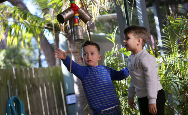 Boys playing with hanging cans outside