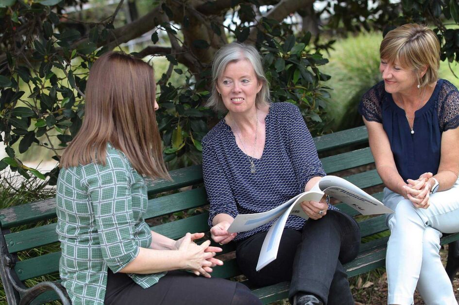 Emma Vanna and Deb on bench with book