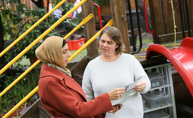 Linda and educator standing and talking with resource