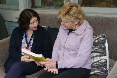 Bernadette seated with educator book