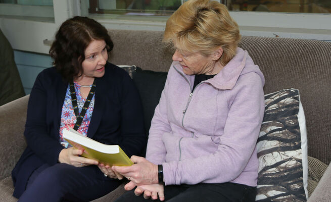 Bernadette seated with educator book