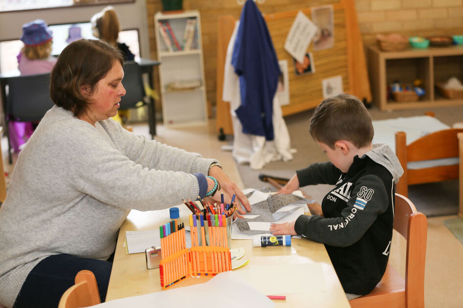 Educator helping child with pasting