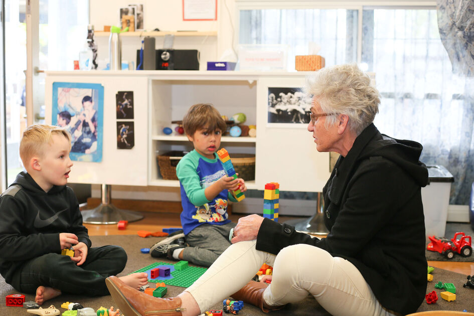 2 boys playing duplo educator talking with one