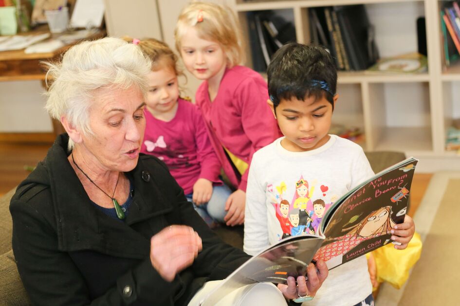 Educator reading to child with 2 in background