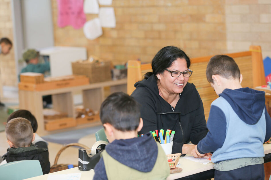 Educator with children at table smiling